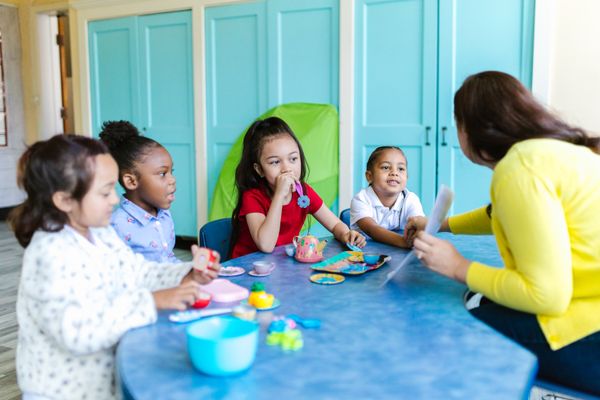 Pre-K children at an activity table with their teacher