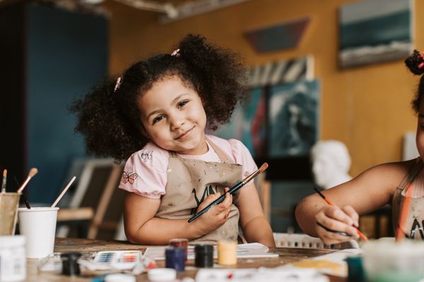 Preschooler painting in an art apron